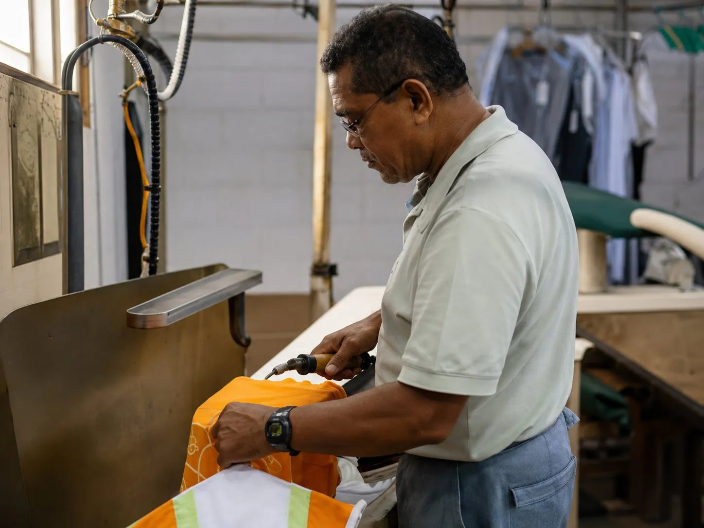 Jorge Saldana finishing a garment by hand at the press